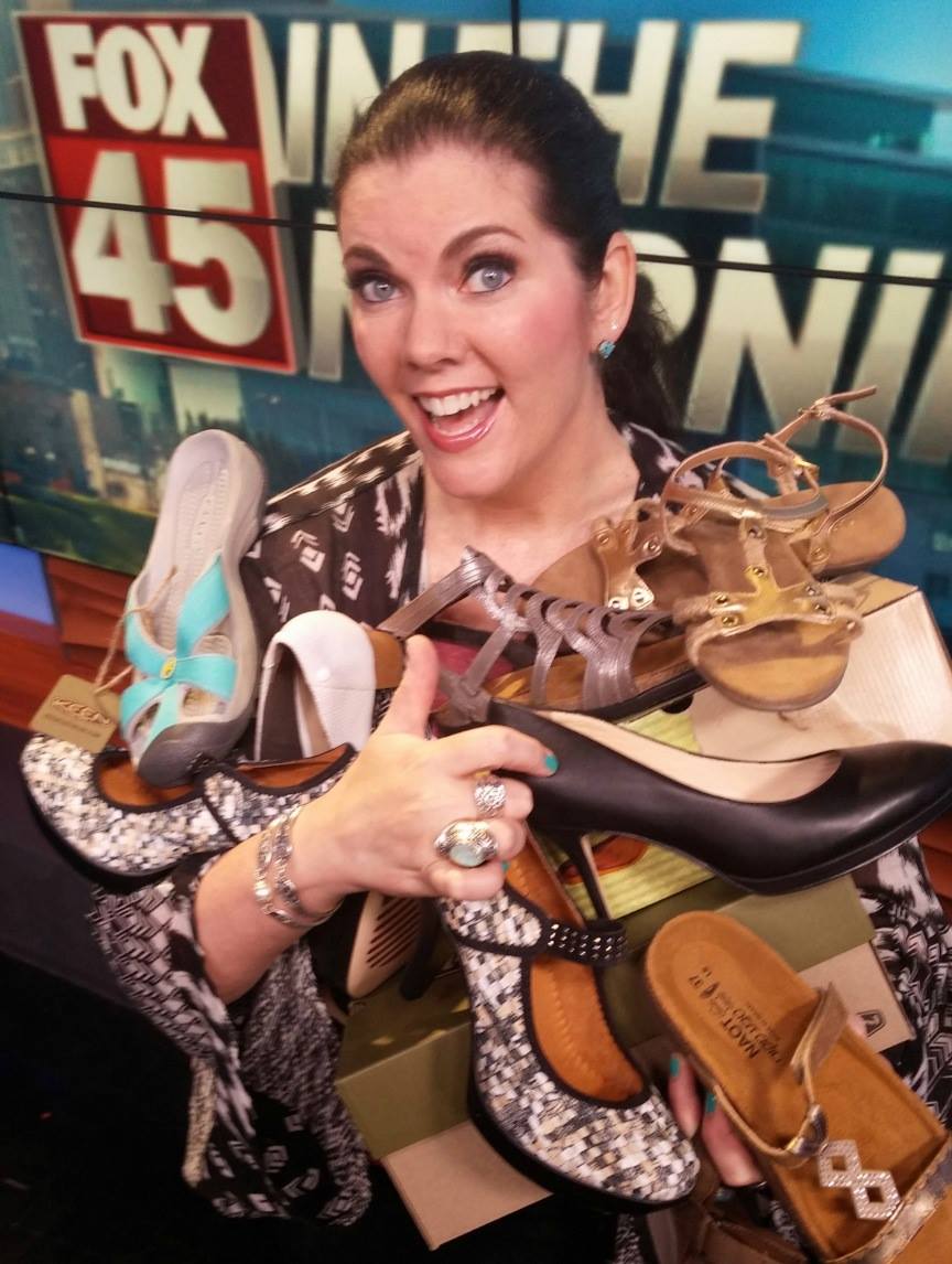 A woman holding many pairs of shoes in her hands.