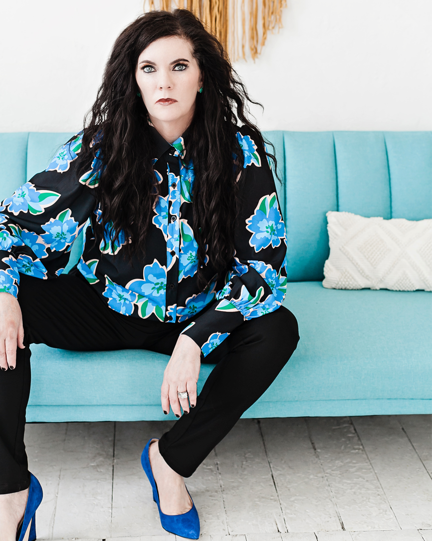 A woman sitting on top of a couch wearing blue shoes.