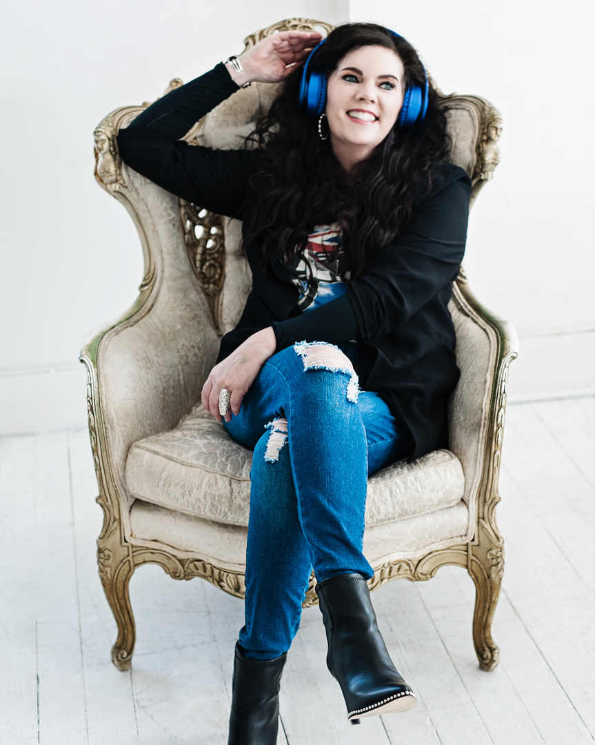 A woman sitting in a chair wearing blue headphones.